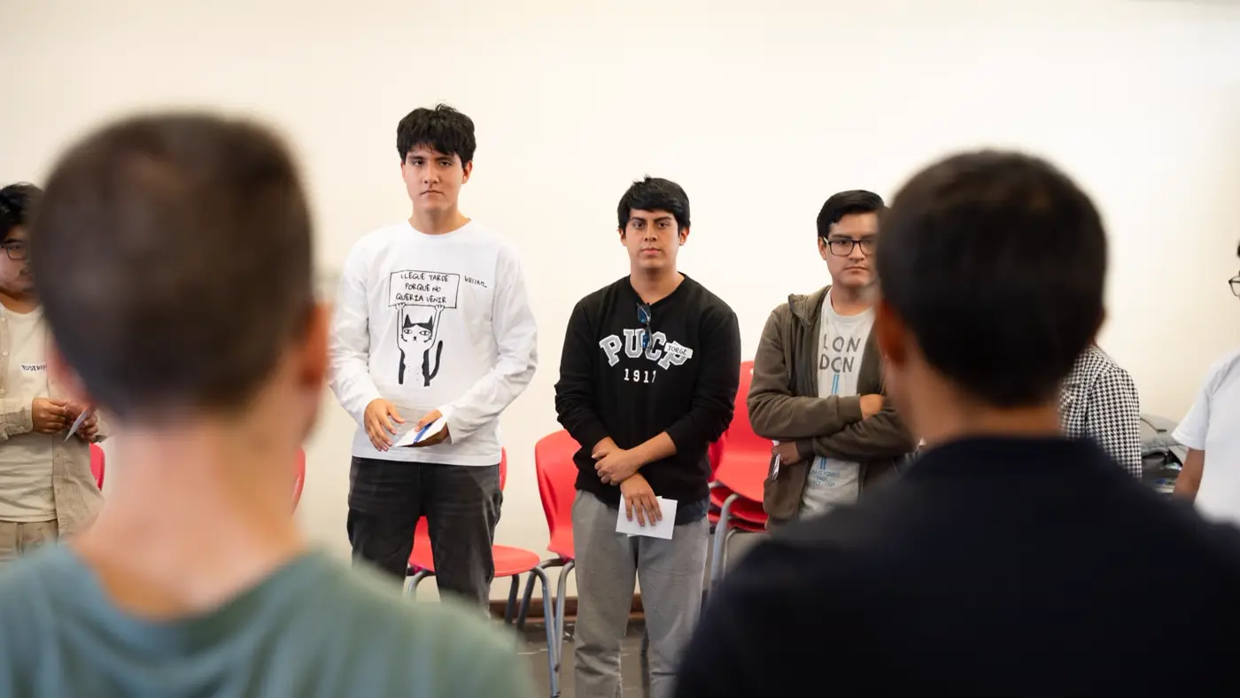 Tres estudiantes de pie con sus tarjetas frente al grupo