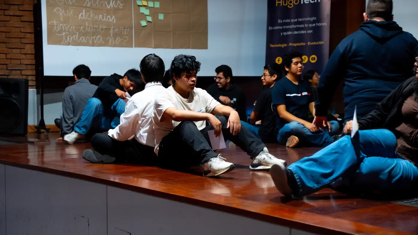 Grupo de estudiantes sentados en el escenario durante una dinámica