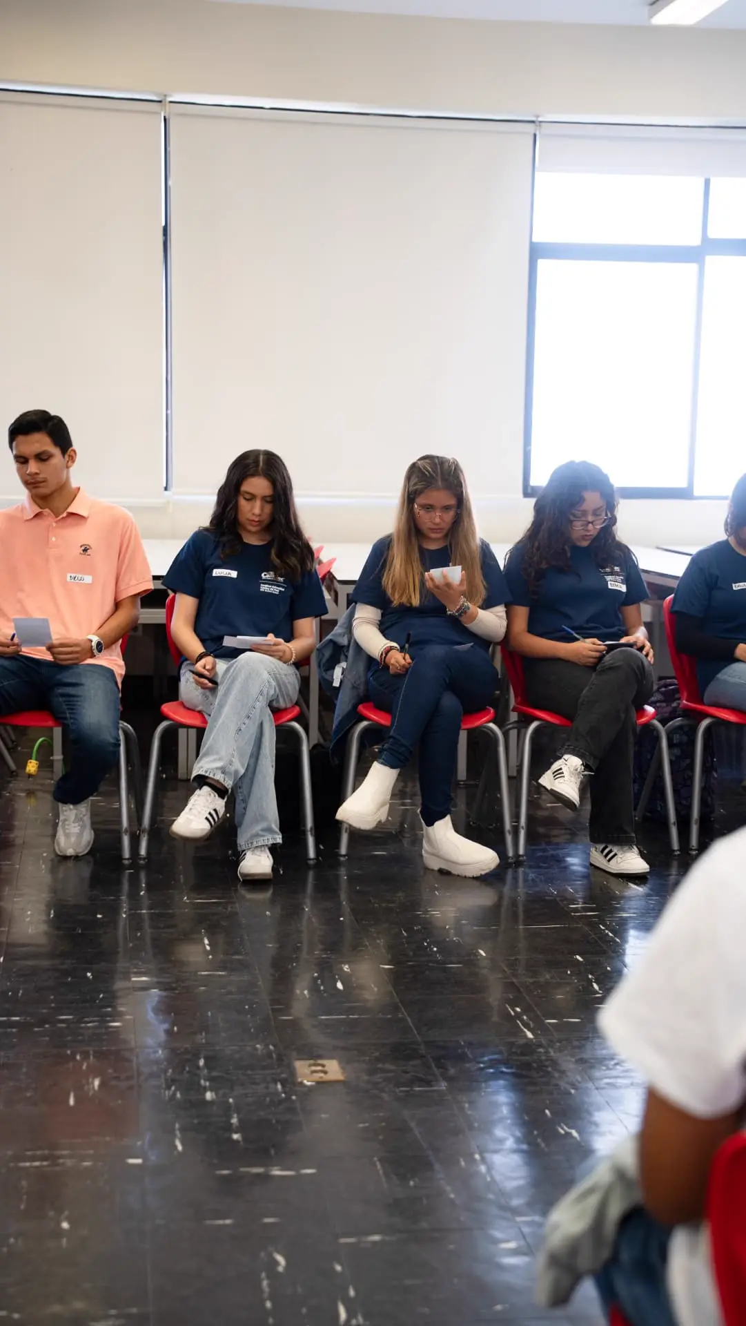 Estudiantes sentados leyendo y escribiendo sus tarjetas