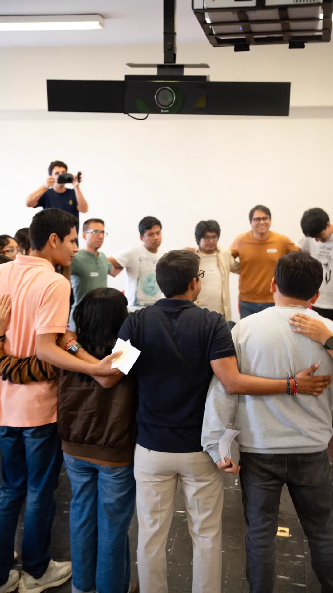 Grupo de participantes abrazados en círculo al cierre del taller