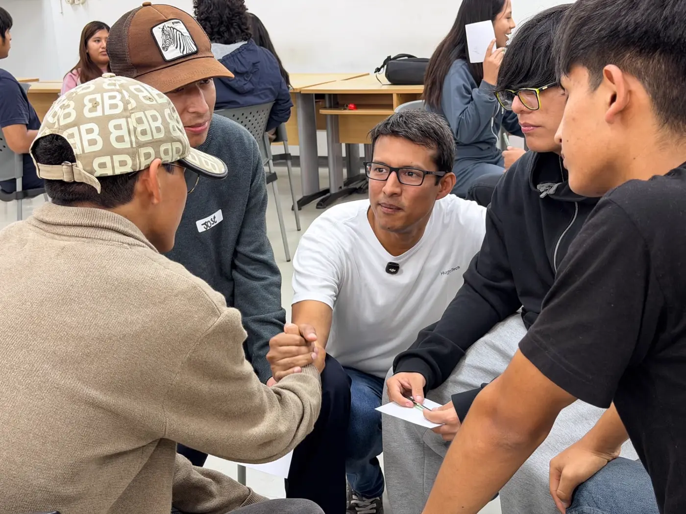 Estudiantes sentados en círculo dándose la mano durante una dinámica