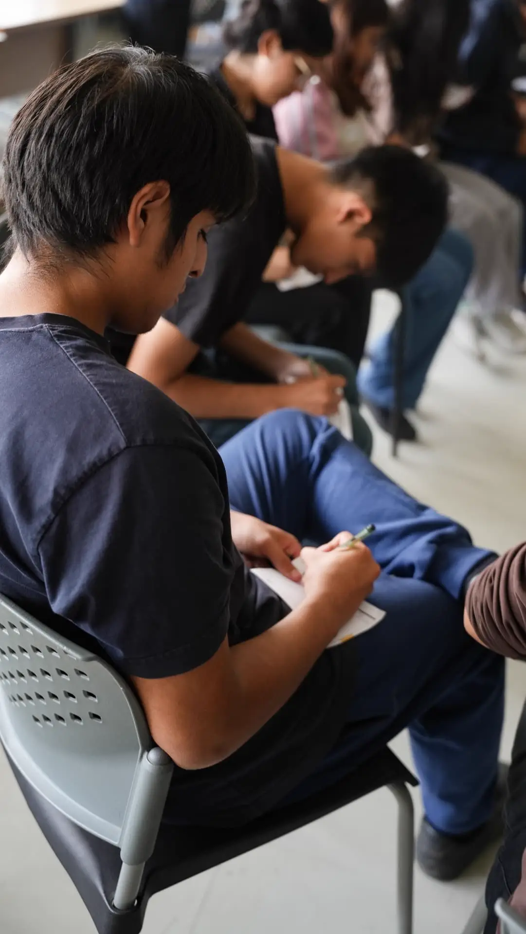 Estudiantes sentados escribiendo en sus tarjetas