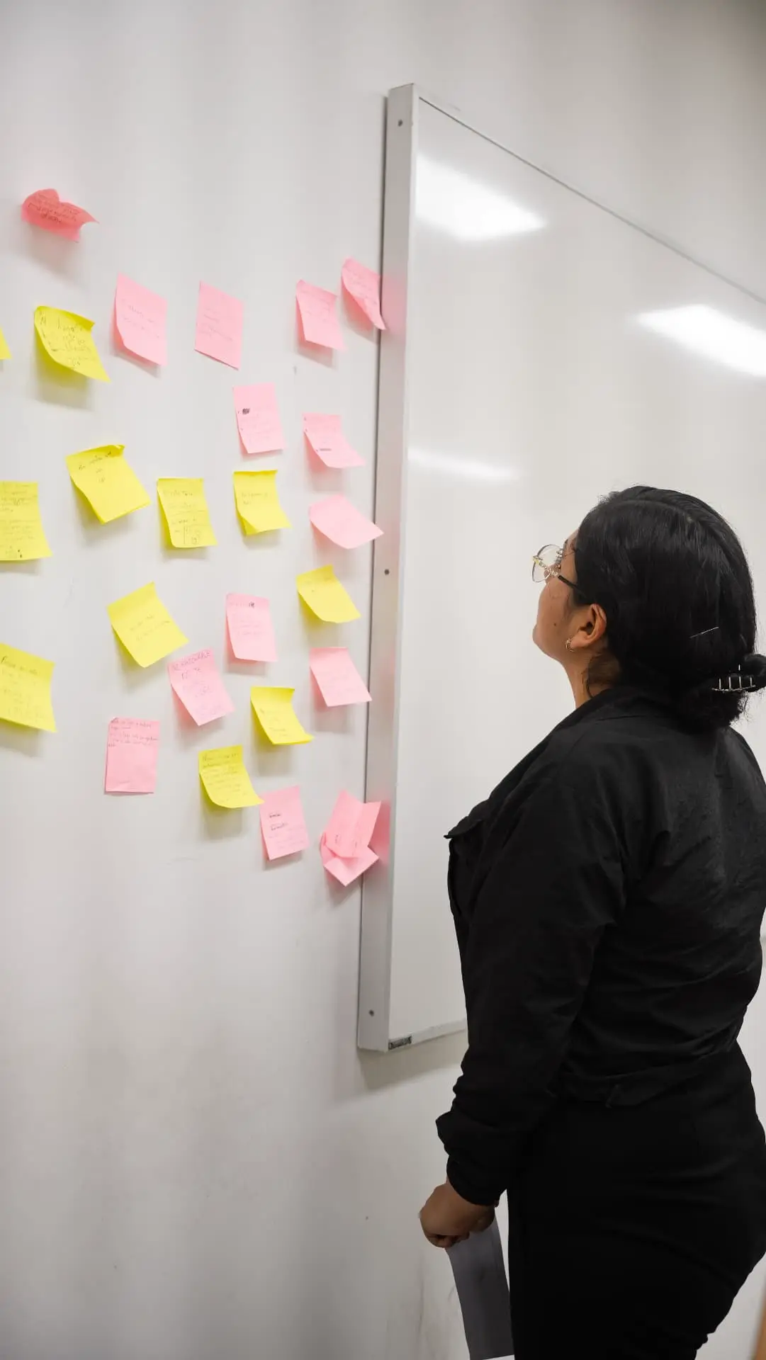 Participante mirando el muro lleno de post-its del taller